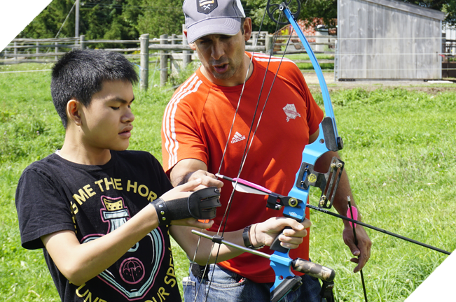 Male staff guiding a youth in archery